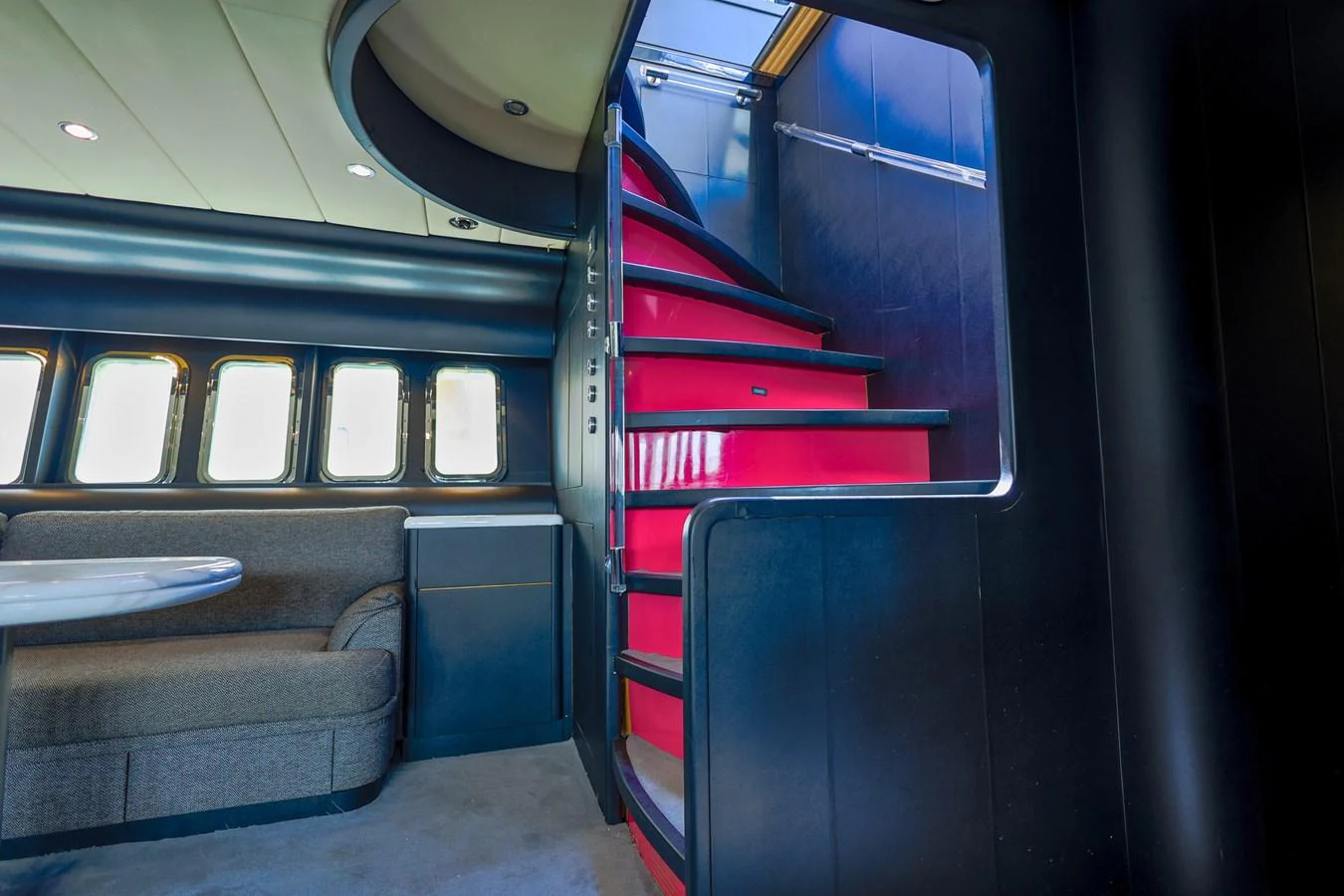A stylish interior featuring a striking red staircase and a comfortable seating area. aboard SEA SQUIRTER Yacht for Sale