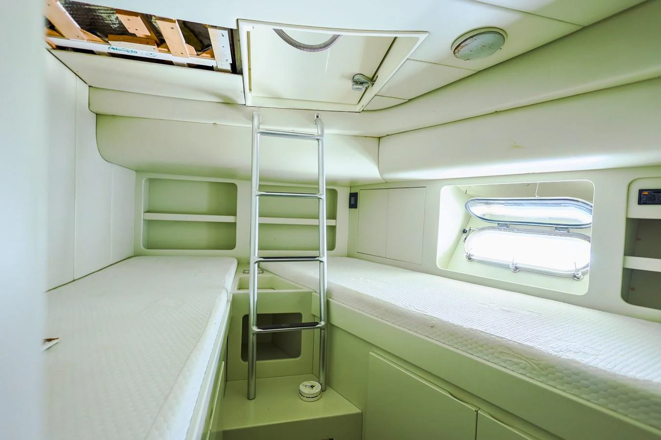 A cozy cabin with twin beds and a ladder leading to an overhead hatch. aboard SEA SQUIRTER Yacht for Sale