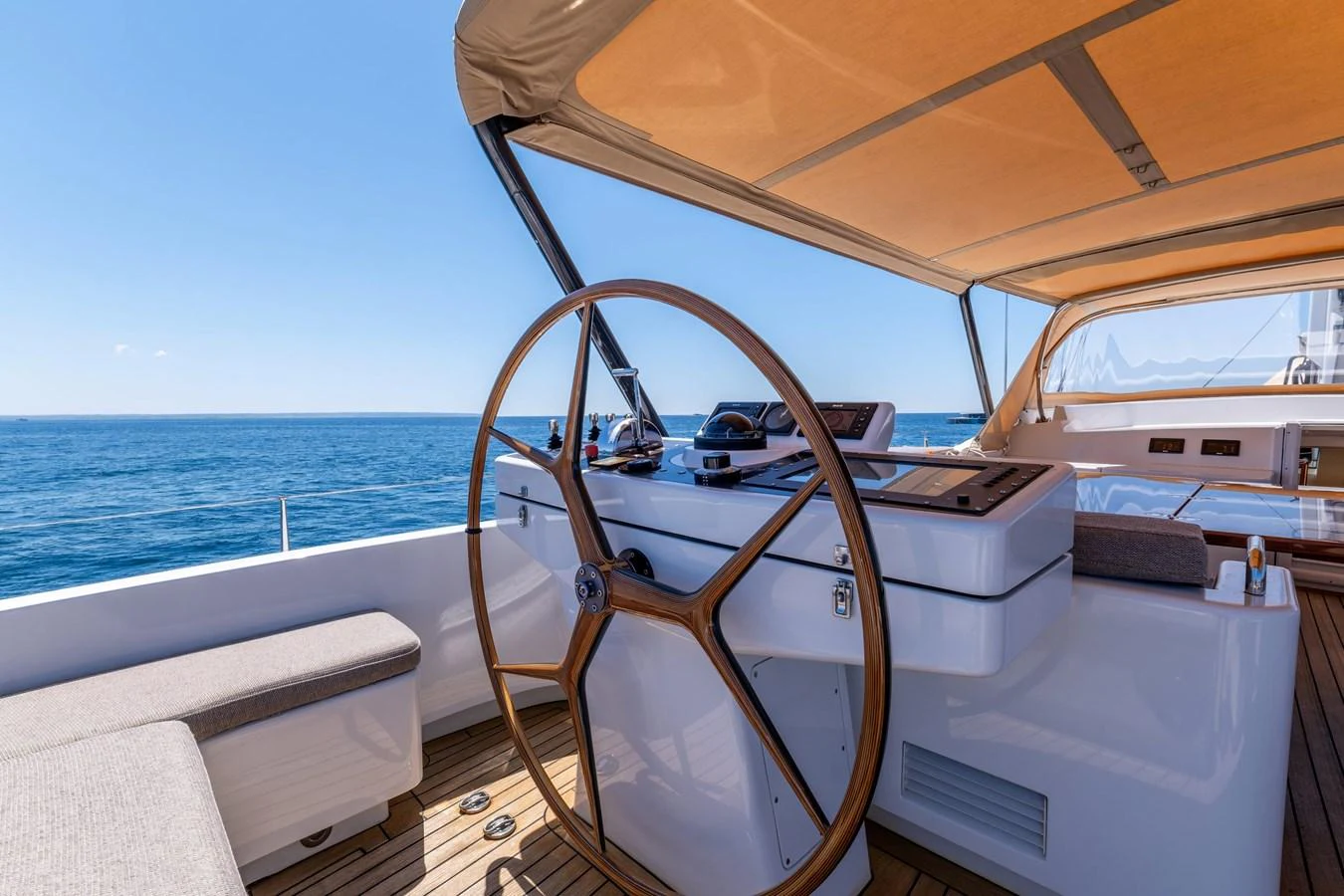 The helm station features a large wooden steering wheel with a stunning ocean view. aboard EPIPHANY Yacht for Sale