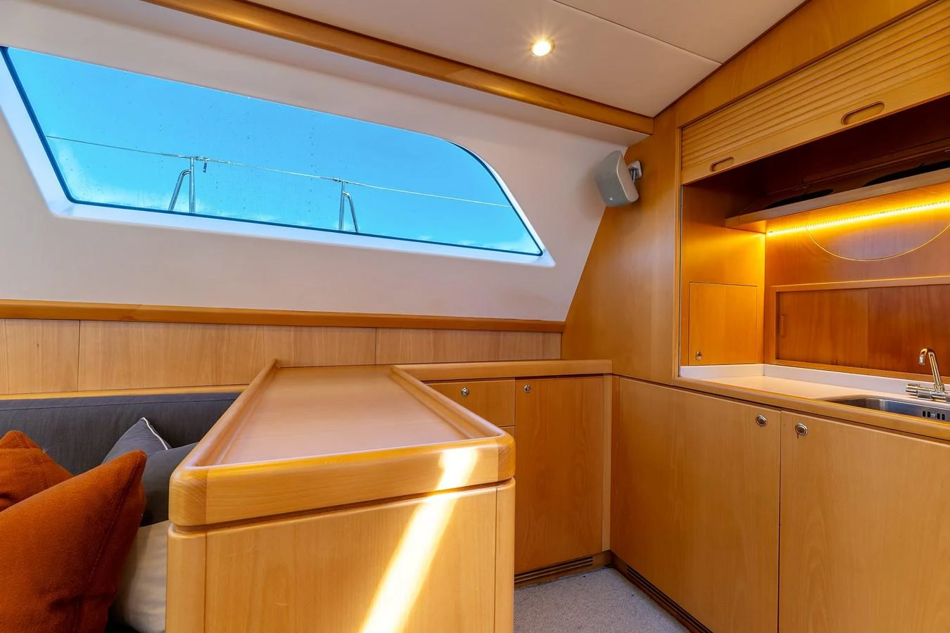 The yacht's interior features a cozy seating area with warm wooden finishes and a large window providing ample natural light. aboard EPIPHANY Yacht for Sale
