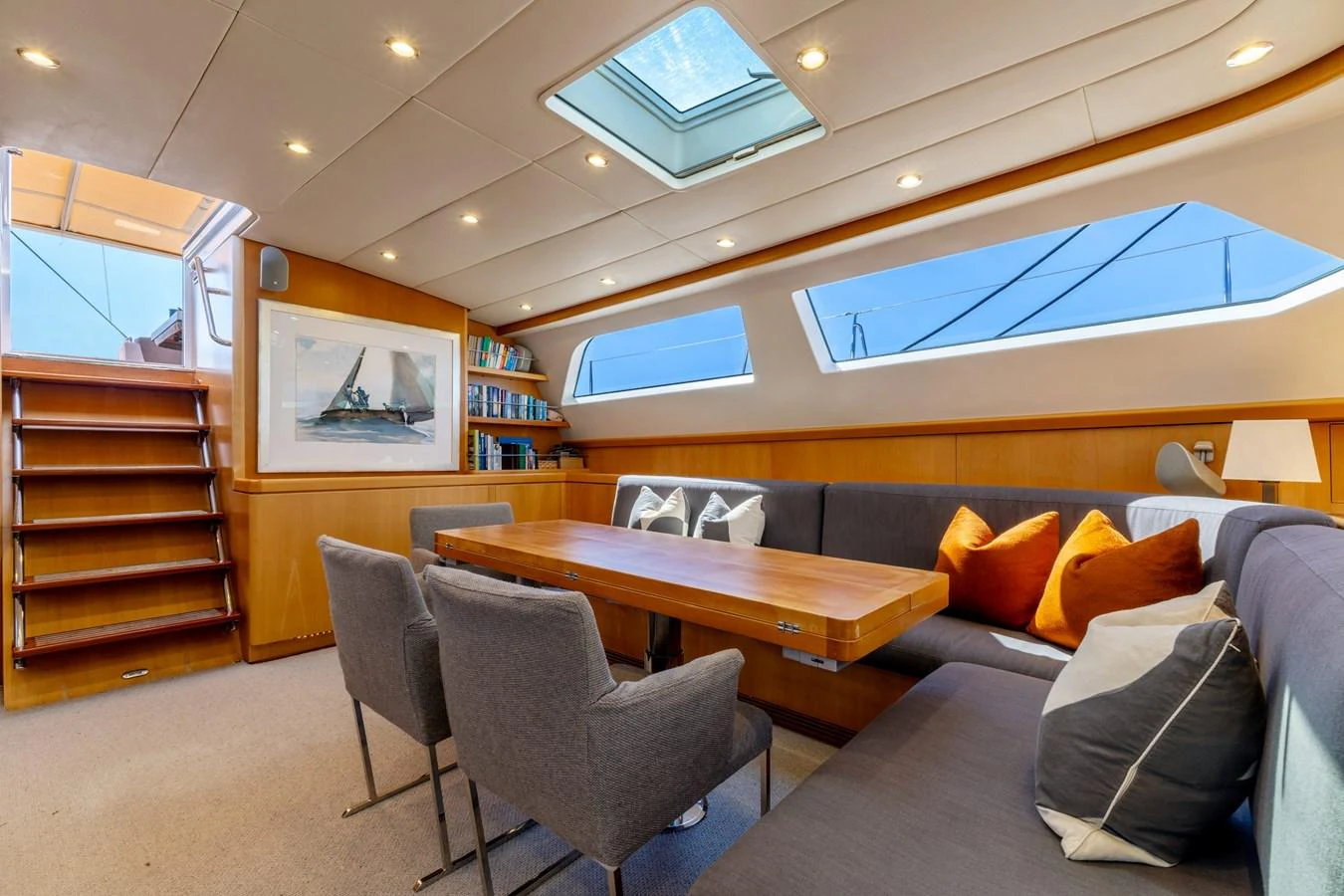 The salon features a comfortable seating area with a wooden table, plush chairs, and ample natural light from large windows and a skylight. aboard EPIPHANY Yacht for Sale