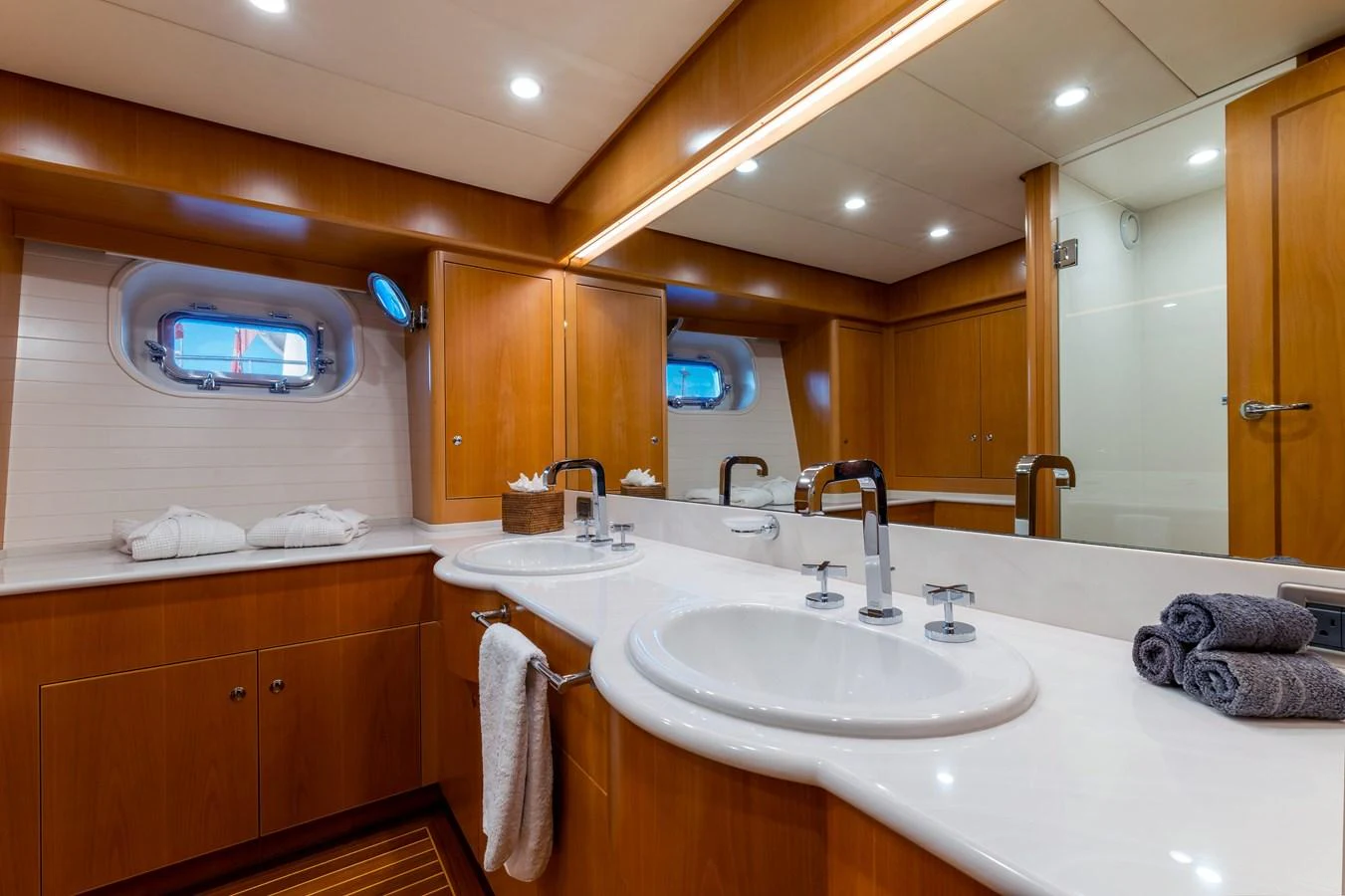 The yacht's bathroom features elegant wood cabinetry, dual sinks, and a spacious shower area. aboard EPIPHANY Yacht for Sale
