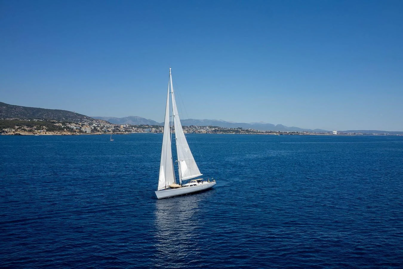 A sleek sailing yacht glides gracefully across the open sea under clear blue skies. aboard EPIPHANY Yacht for Sale