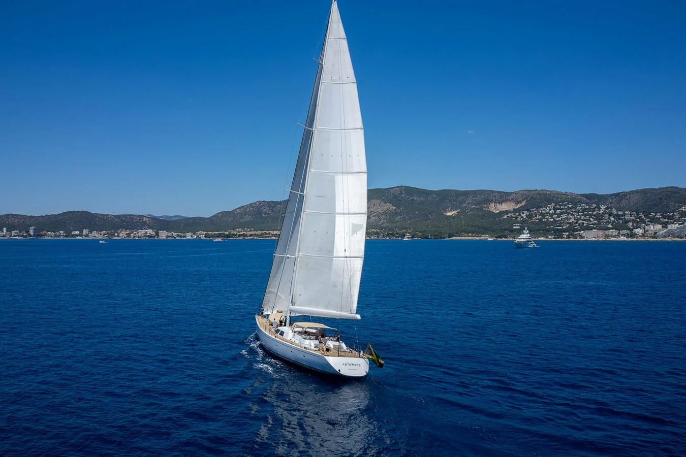 A sleek sailing yacht glides gracefully across the deep blue sea under clear skies. aboard EPIPHANY Yacht for Sale