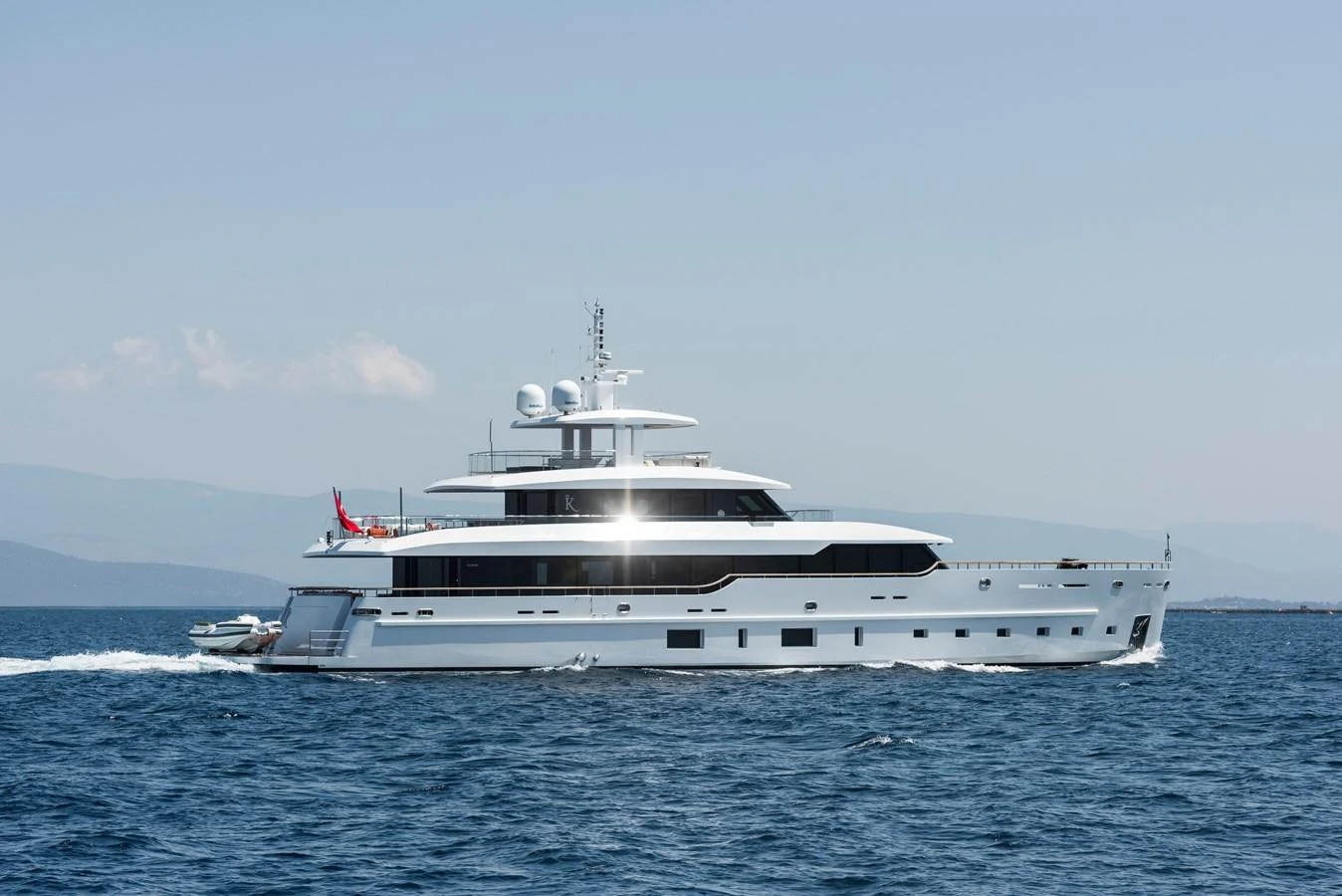 A sleek and modern yacht cruises through calm blue waters under a clear sky. aboard K Yacht for Sale