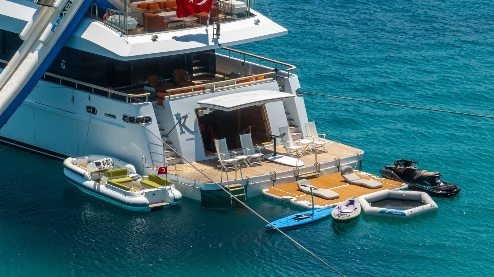 The yacht's aft deck features a luxurious lounging area with direct access to various water toys and tenders. aboard K Yacht for Sale