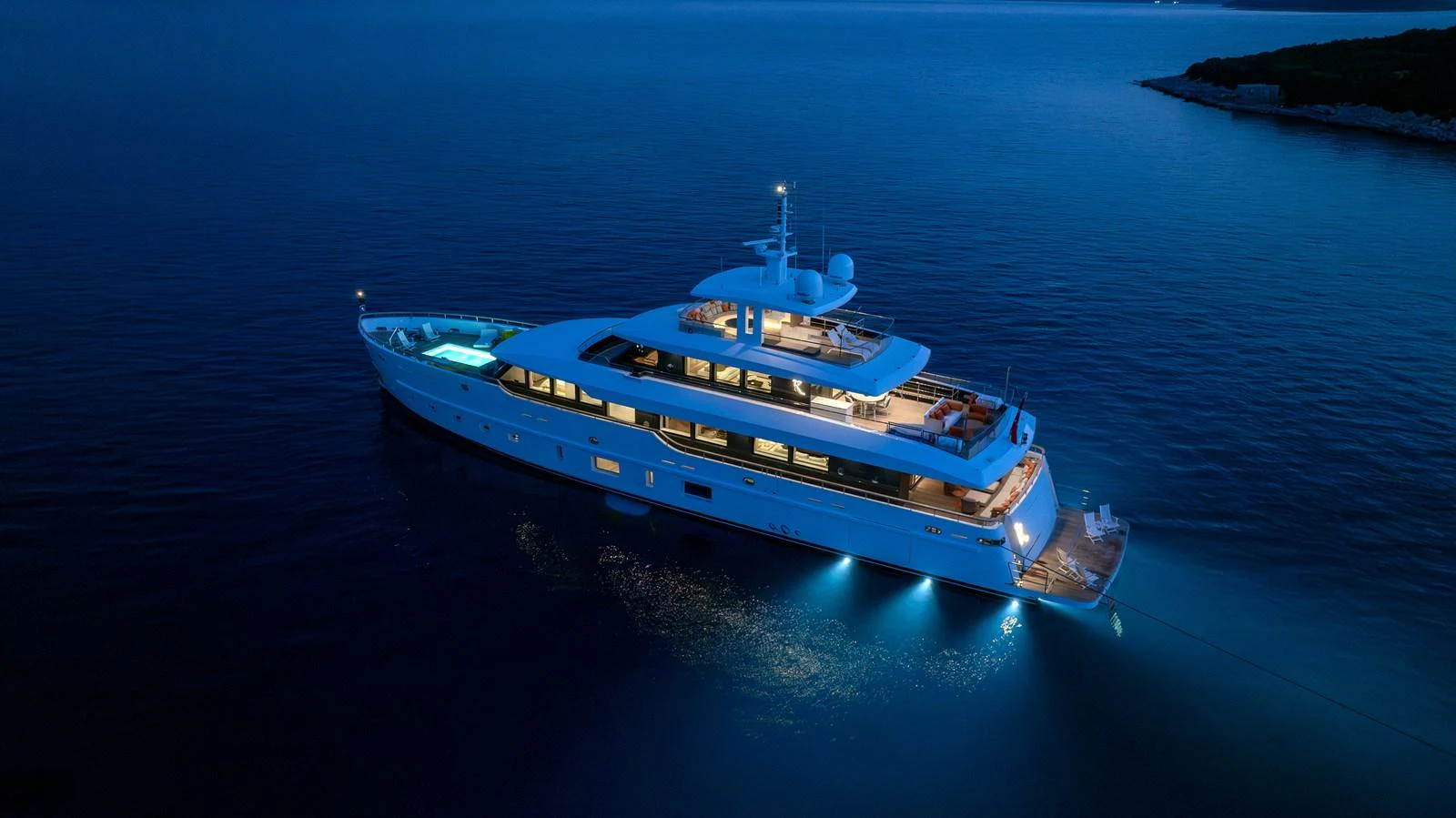 A luxurious yacht is beautifully illuminated at dusk, showcasing its elegant design and serene surroundings. aboard K Yacht for Sale