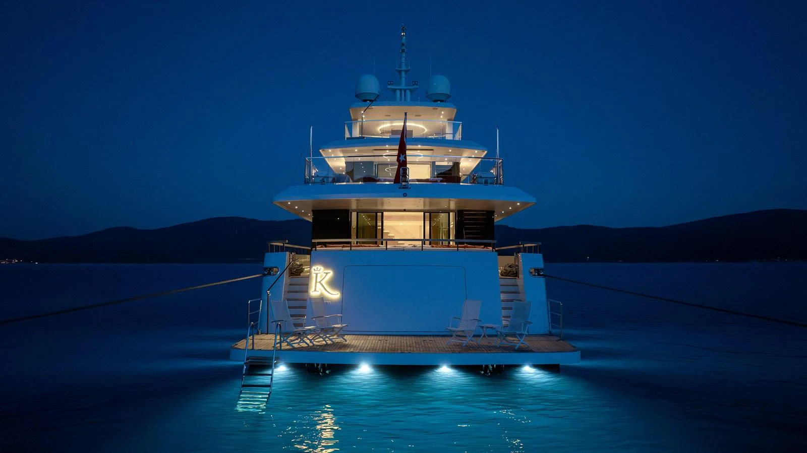 A luxurious yacht is beautifully illuminated at night, showcasing its elegant design and serene surroundings. aboard K Yacht for Sale