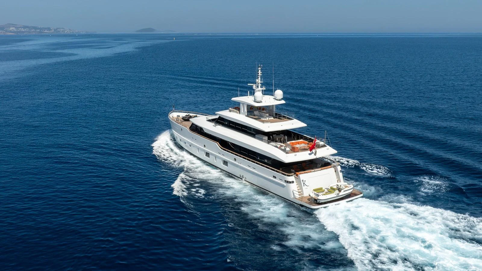 A luxurious yacht cruises through clear blue waters, showcasing its elegant design and spacious decks. aboard K Yacht for Sale
