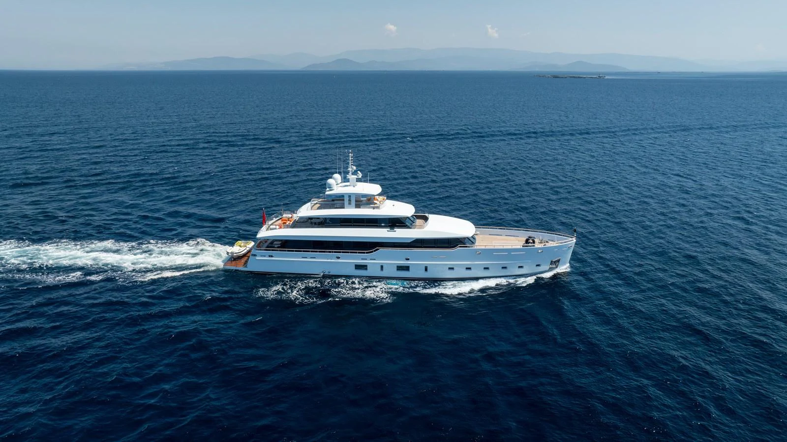 A sleek yacht glides effortlessly across the open sea under a clear blue sky. aboard K Yacht for Sale