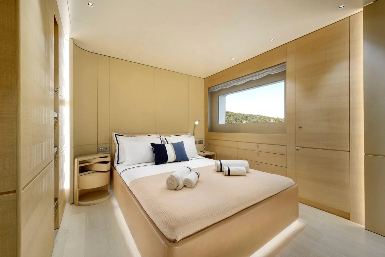 The stateroom features a luxurious bed with elegant linens and a scenic window view. aboard K Yacht for Sale