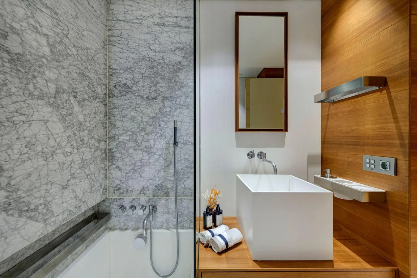 A luxurious bathroom featuring a marble shower and a modern sink with wooden accents. aboard K Yacht for Sale