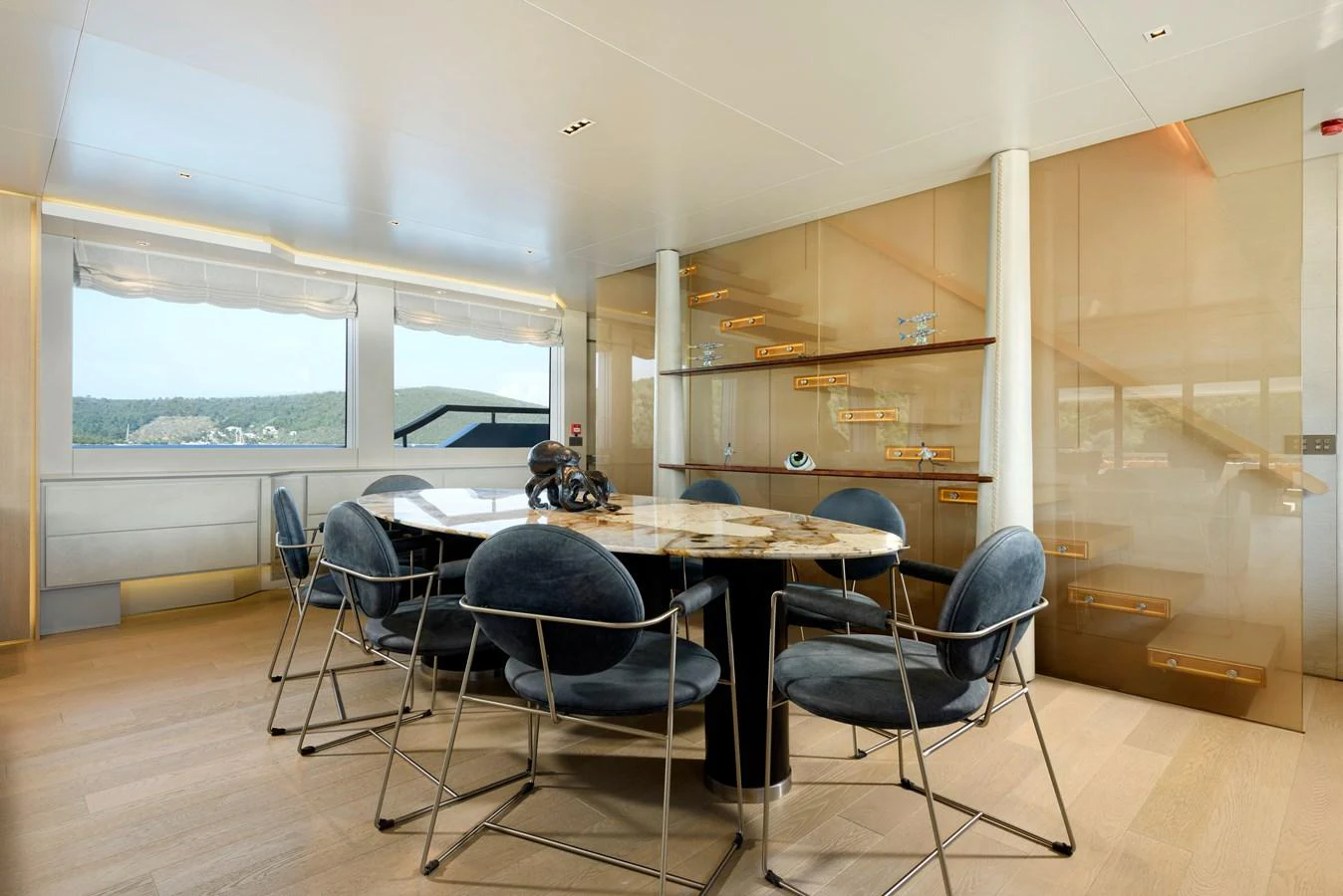 The yacht's dining area features a modern table with plush chairs and large windows offering scenic views. aboard K Yacht for Sale
