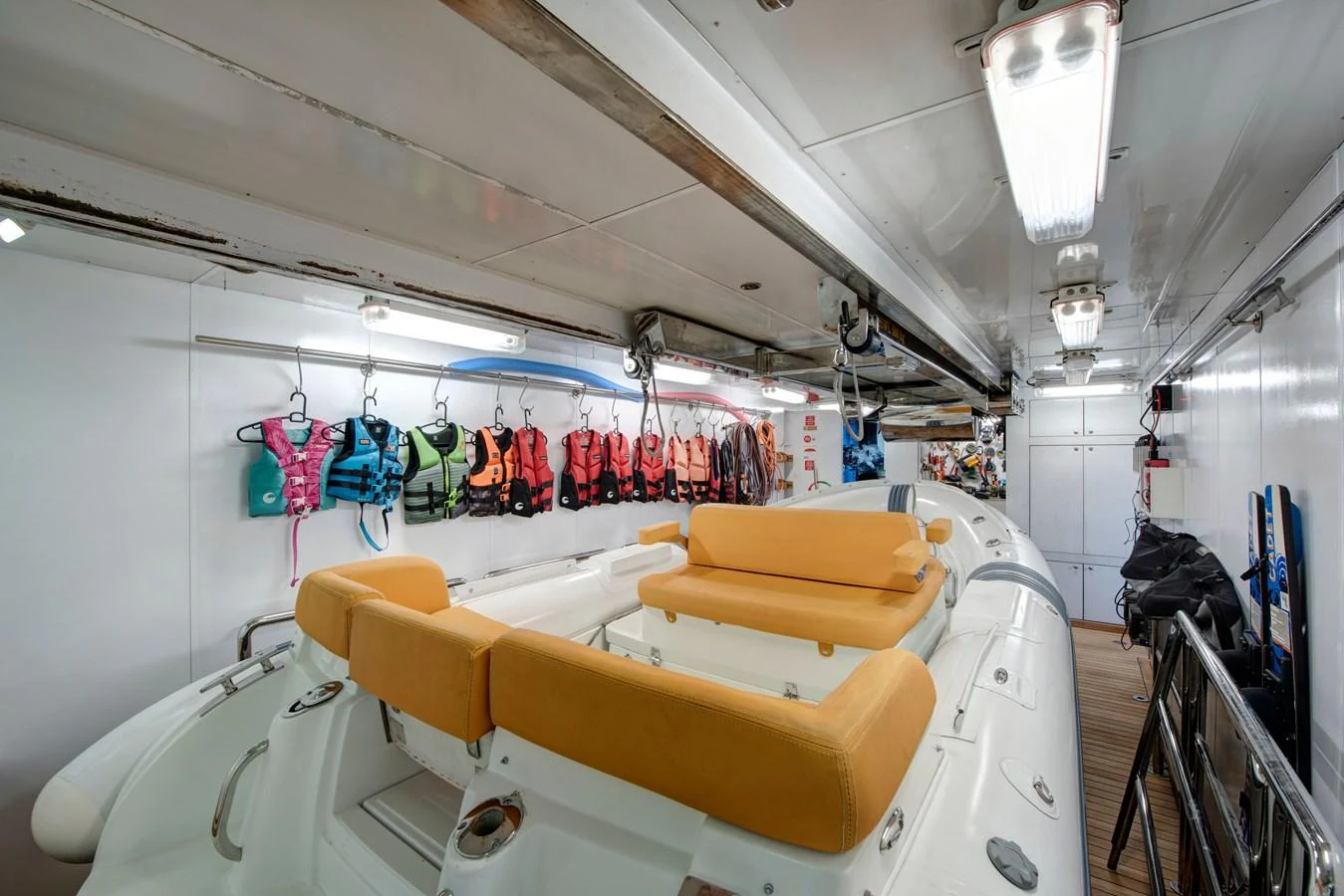 A well-organized tender garage featuring a sleek tender boat and various life jackets. aboard K Yacht for Sale