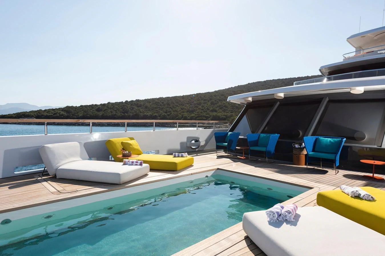 The sundeck features a luxurious pool surrounded by comfortable lounging areas with vibrant cushions. aboard K Yacht for Sale