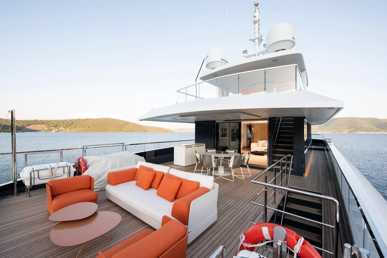 The yacht's aft deck features a stylish outdoor seating area with vibrant orange cushions and modern furnishings. aboard K Yacht for Sale
