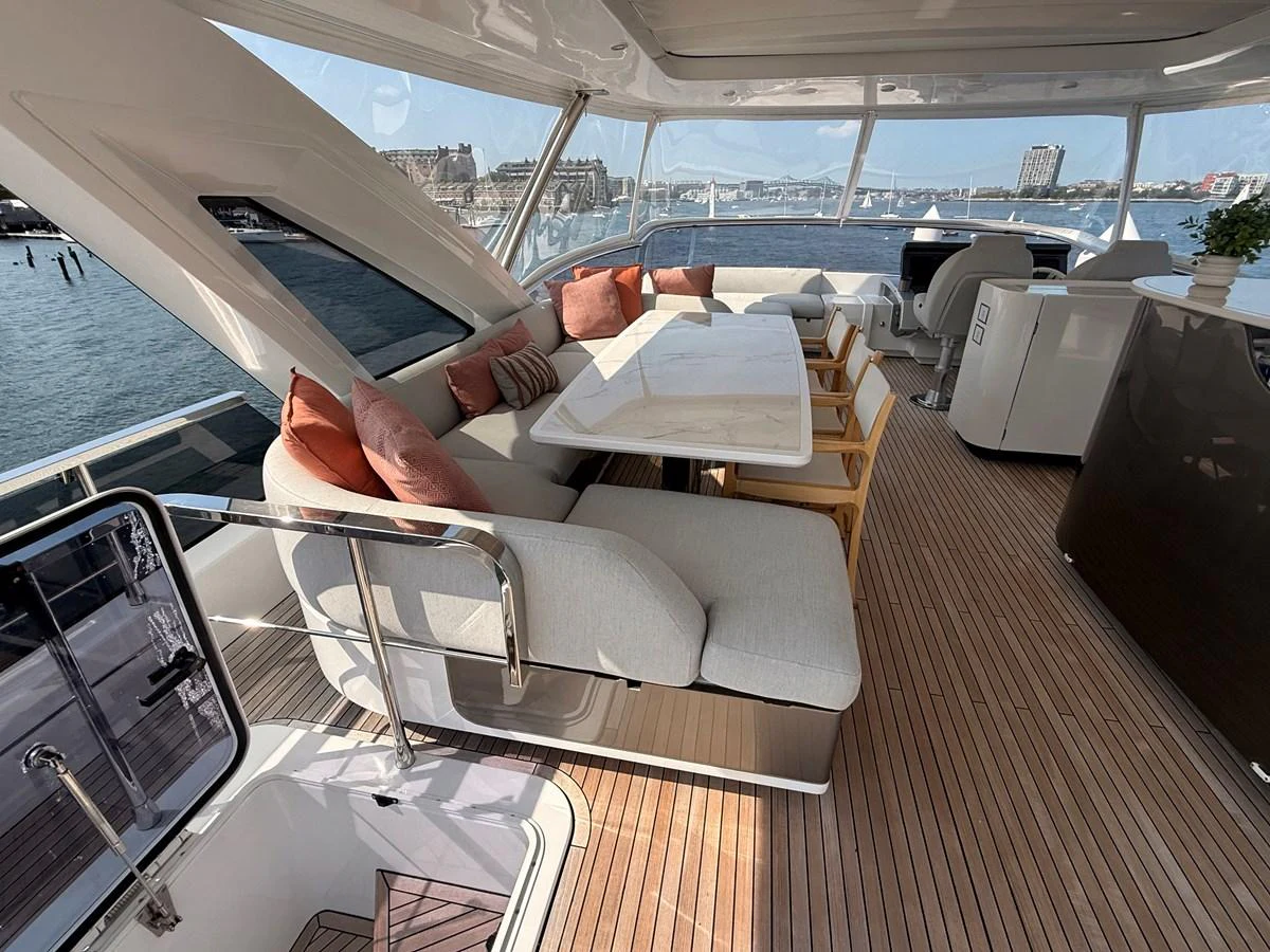 The flybridge features a spacious seating area with a dining table and panoramic views. aboard 2022 AZIMUT GRANDE 25M Yacht for Sale