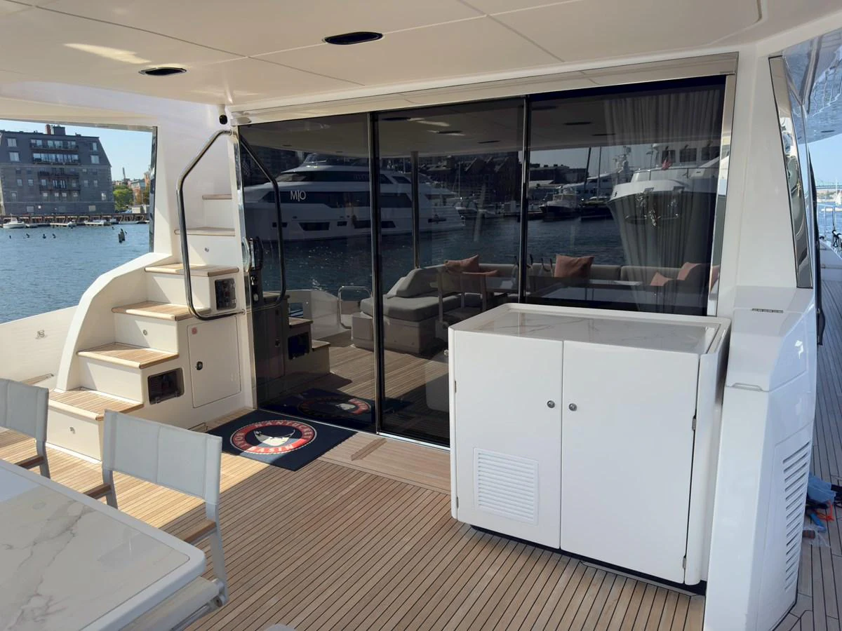 The aft deck features a comfortable seating area with easy access to the interior and a view of the marina. aboard 2022 AZIMUT GRANDE 25M Yacht for Sale