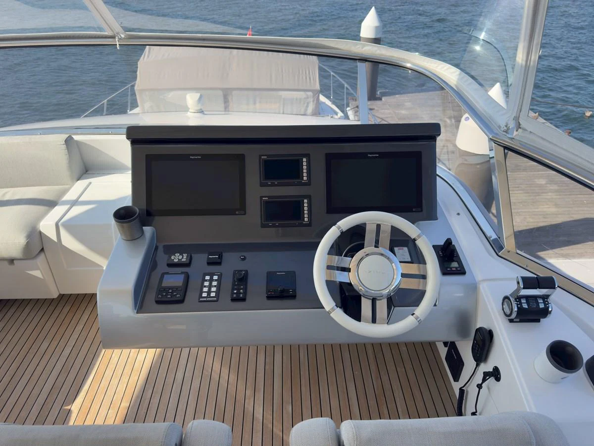 The helm station features modern navigation equipment and a sleek steering wheel, set against a backdrop of teak decking. aboard 2022 AZIMUT GRANDE 25M Yacht for Sale