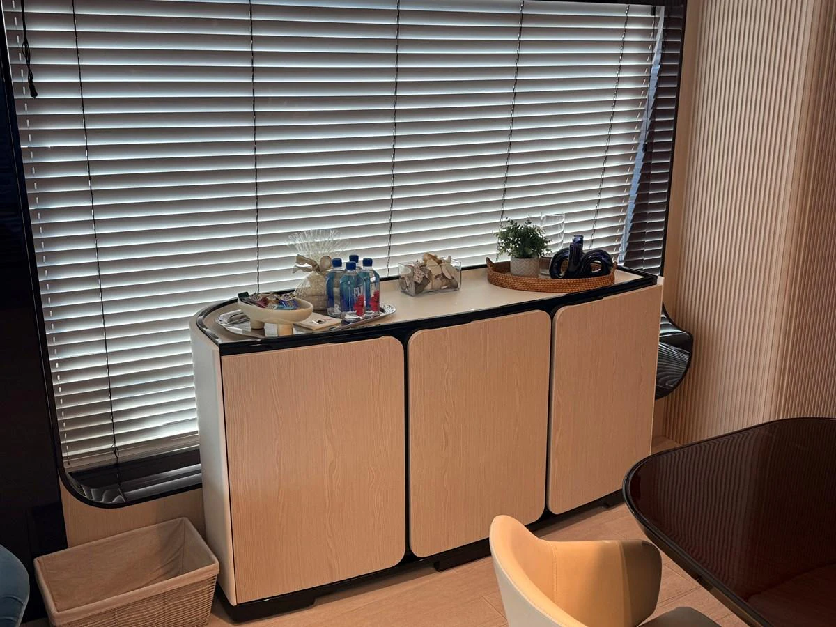 The image showcases a stylish interior space with a modern cabinet and a large window with blinds. aboard 2022 AZIMUT GRANDE 25M Yacht for Sale