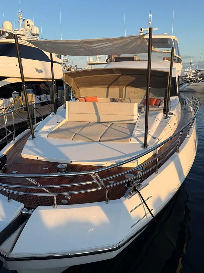 The yacht's foredeck features a spacious sunbathing area with comfortable cushions and a shade canopy. aboard 2022 AZIMUT GRANDE 25M Yacht for Sale