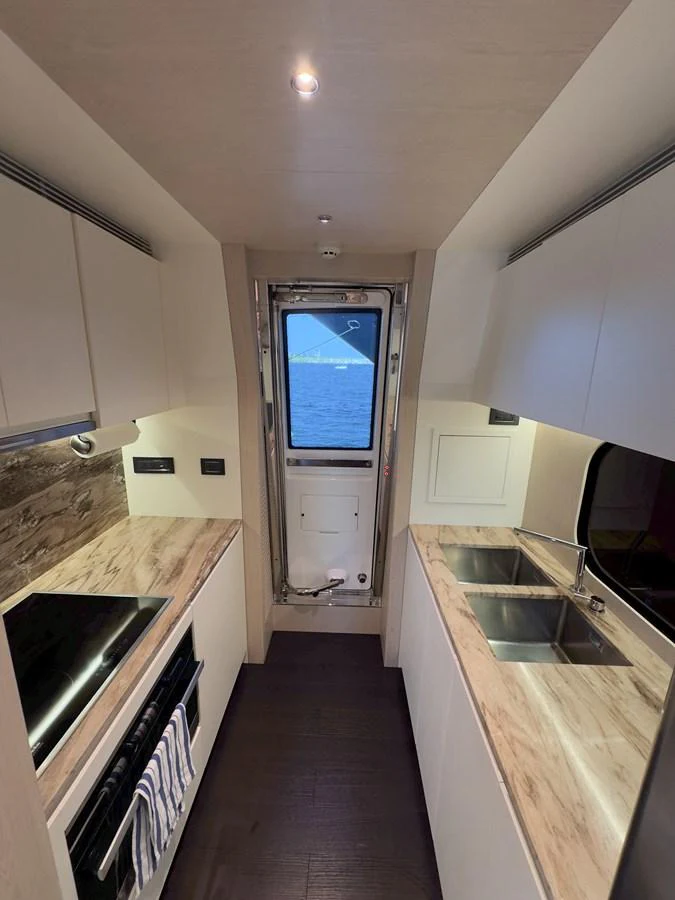 The galley features modern appliances and a sleek design with a view of the sea through the door. aboard 2022 AZIMUT GRANDE 25M Yacht for Sale