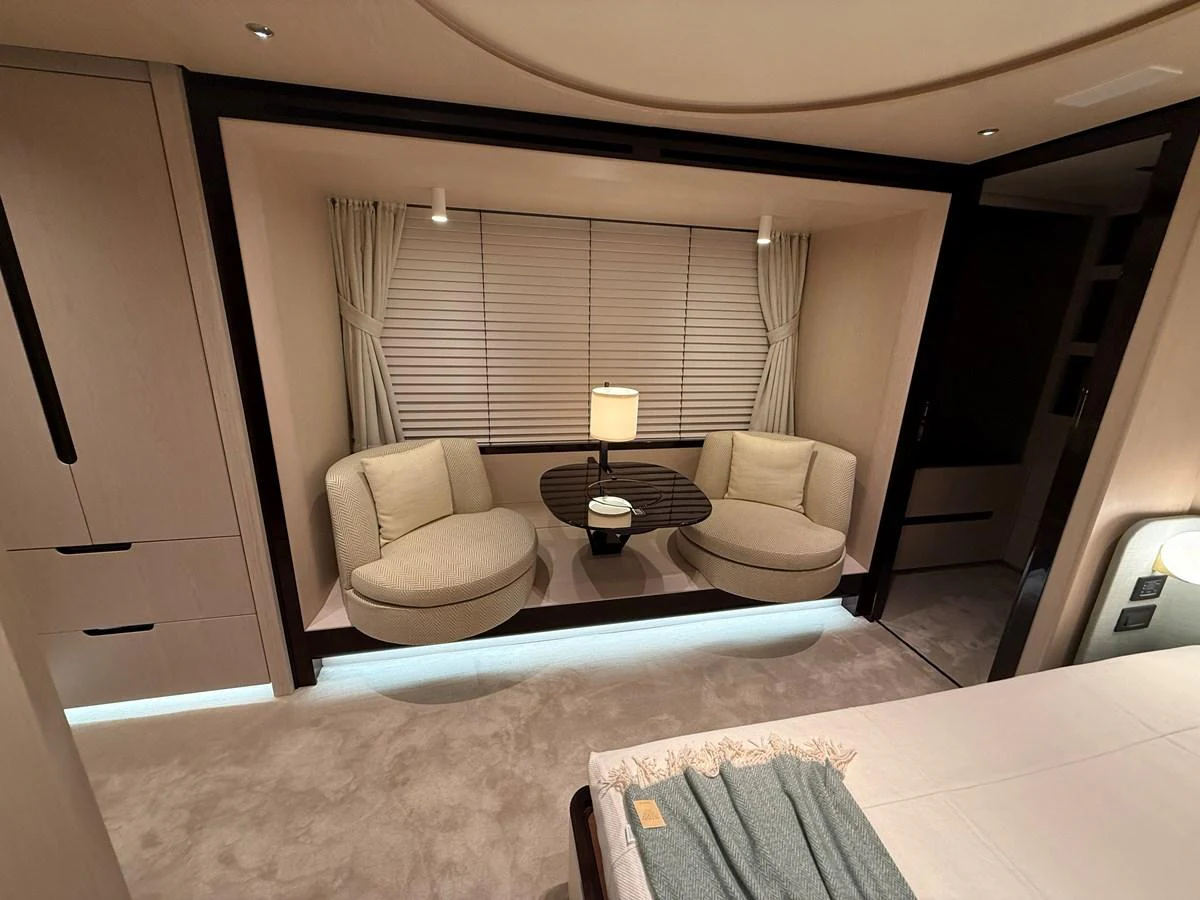 The stateroom features a cozy seating area with plush chairs and a central table, illuminated by soft lighting. aboard 2022 AZIMUT GRANDE 25M Yacht for Sale