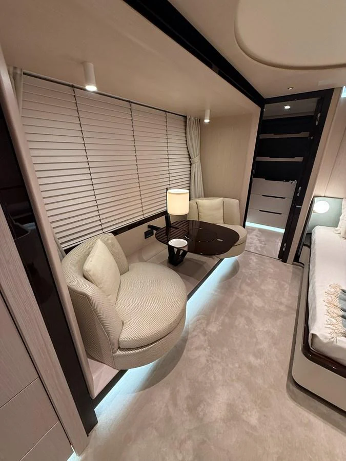 The stateroom features a cozy seating area with plush chairs and a modern table, complemented by soft lighting and elegant decor. aboard 2022 AZIMUT GRANDE 25M Yacht for Sale