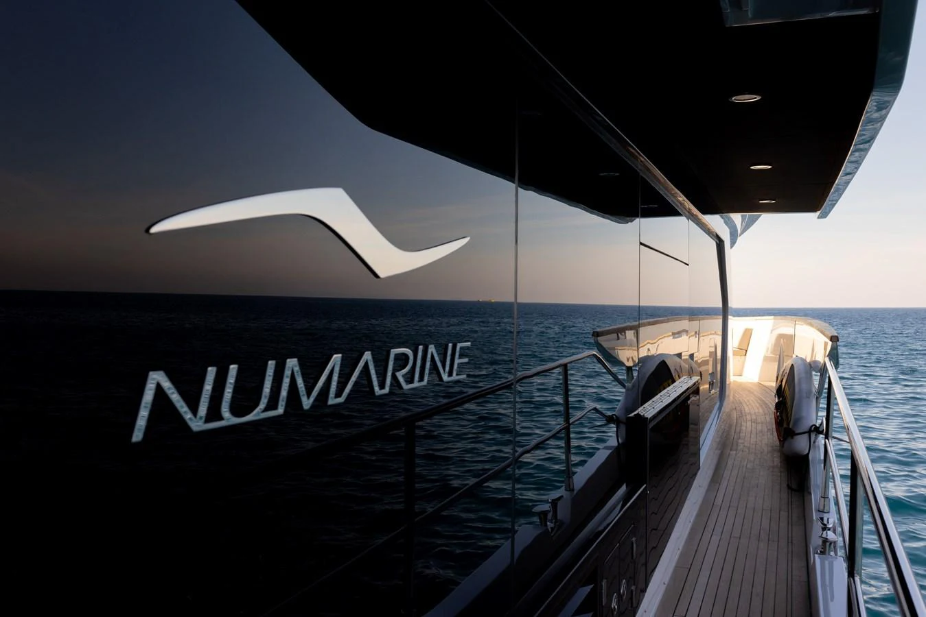 A sleek yacht with reflective windows cruising on calm waters at sunset. aboard KAMOKA Yacht for Sale