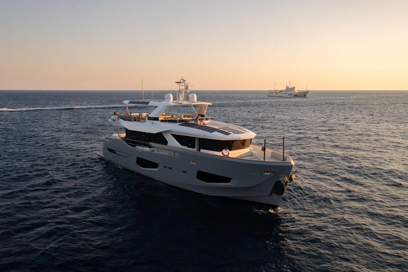 A sleek and modern yacht cruises gracefully on the open sea at sunset. aboard KAMOKA Yacht for Sale