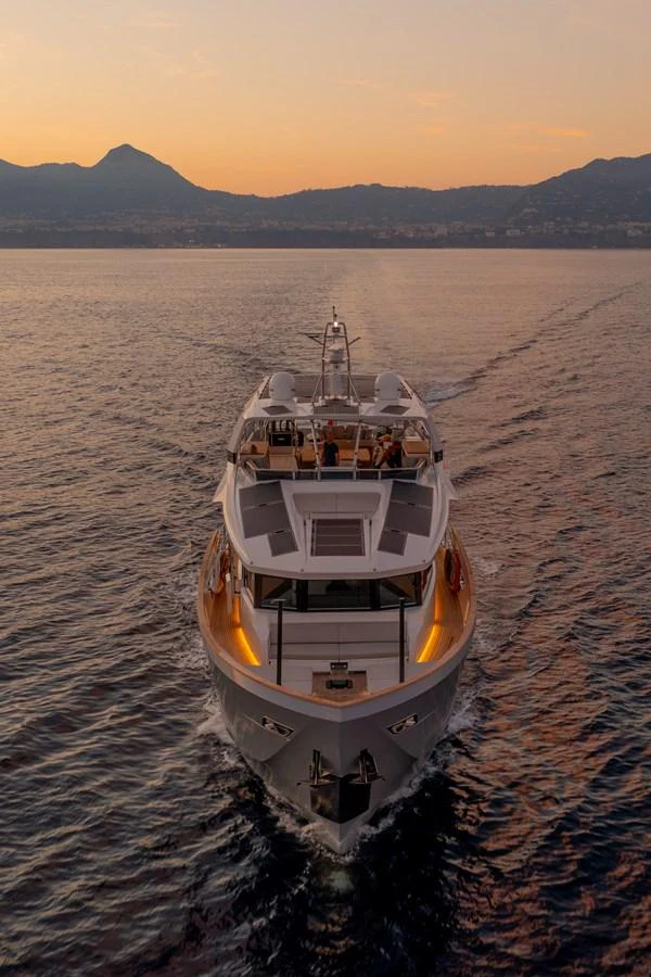A luxurious yacht cruises through calm waters at sunset, showcasing its elegant design and inviting ambiance. aboard KAMOKA Yacht for Sale