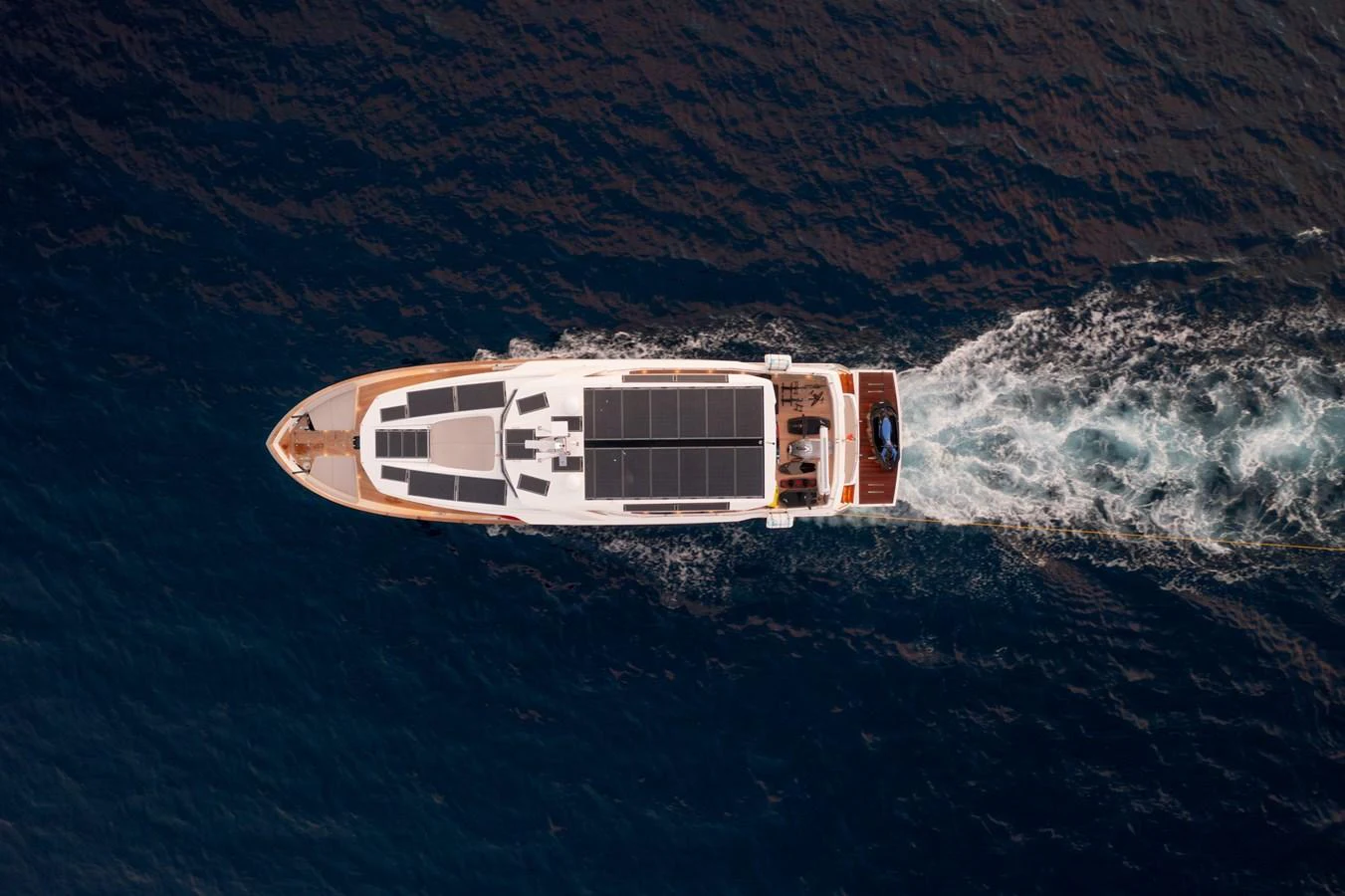 A sleek yacht cruises through deep blue waters, showcasing its modern design from an aerial perspective. aboard KAMOKA Yacht for Sale