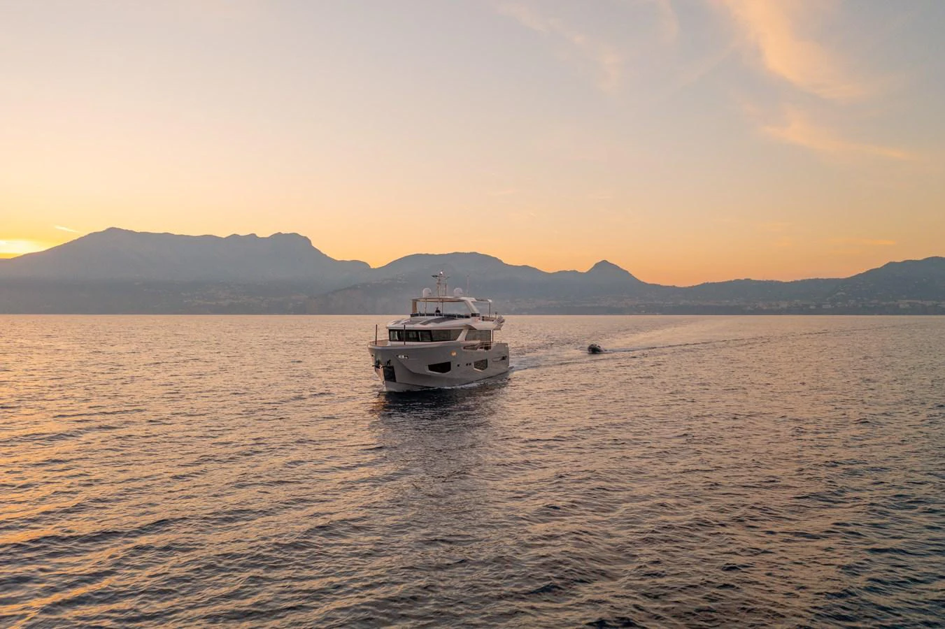 A luxurious yacht cruises serenely on calm waters during a picturesque sunset. aboard KAMOKA Yacht for Sale