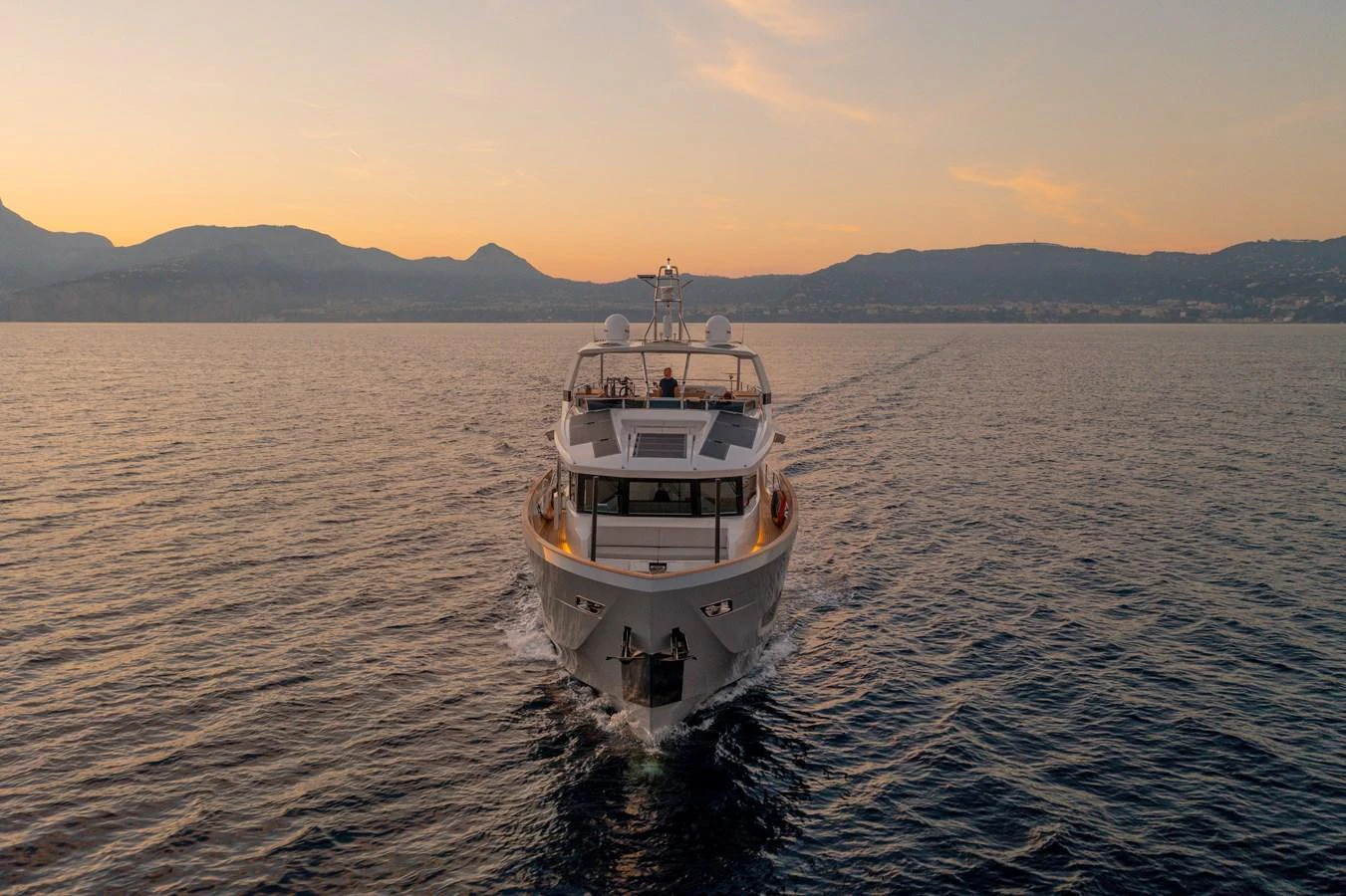 A luxurious yacht cruises through calm waters at sunset, showcasing its elegant design. aboard KAMOKA Yacht for Sale