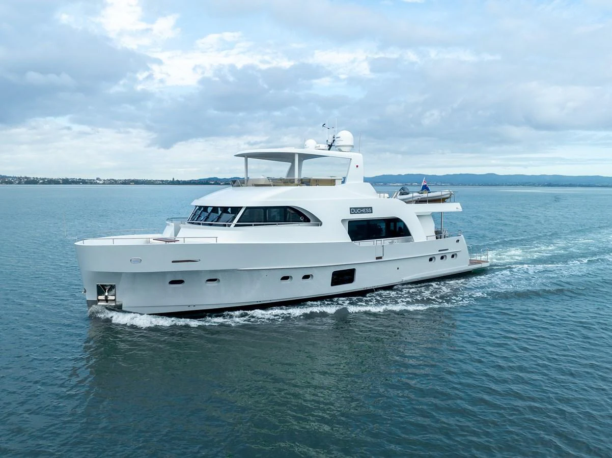 A sleek, modern yacht cruises gracefully on calm waters under a partly cloudy sky. aboard DUTCHESS Yacht for Sale