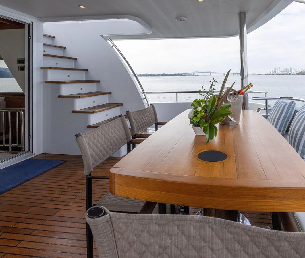 The aft deck features a stylish dining area with a wooden table and comfortable seating, perfect for al fresco meals with a view. aboard DUTCHESS Yacht for Sale