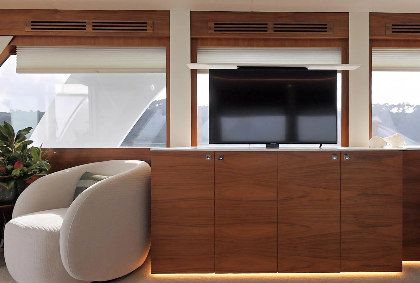 The yacht's interior features a sleek entertainment area with a modern TV and stylish wooden cabinetry. aboard DUTCHESS Yacht for Sale