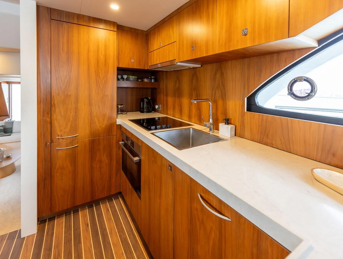 The galley features sleek wooden cabinetry and modern appliances, creating a warm and functional space. aboard DUTCHESS Yacht for Sale