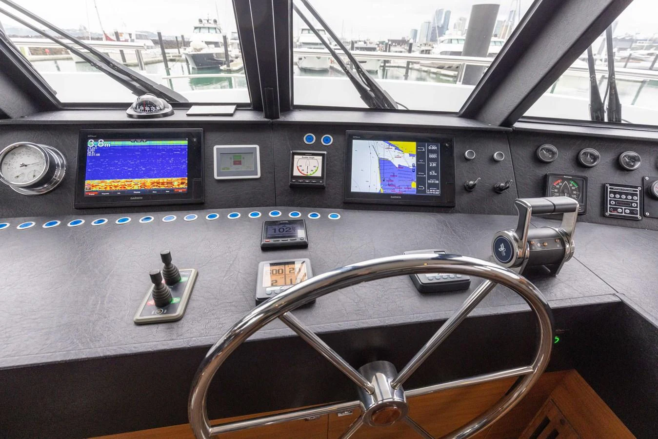 The helm station features advanced navigation equipment and a sleek steering wheel, offering a commanding view of the marina. aboard DUTCHESS Yacht for Sale