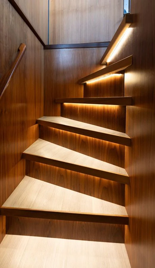 A beautifully crafted wooden staircase with ambient lighting. aboard DUTCHESS Yacht for Sale