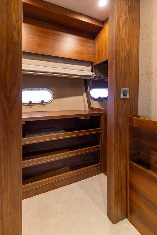 The yacht's interior features a cozy and well-crafted wooden storage area with a porthole window. aboard DUTCHESS Yacht for Sale