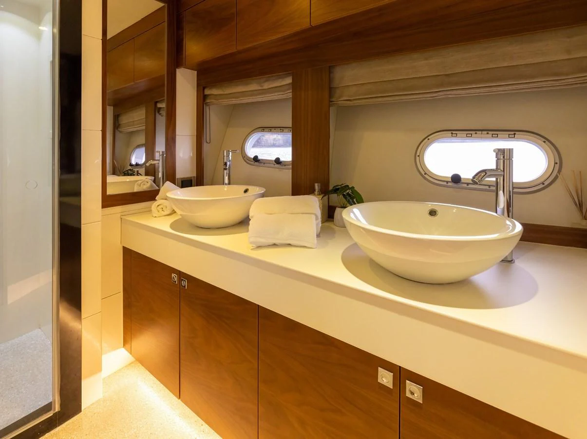 The yacht's bathroom features a double sink vanity with modern fixtures and warm wood accents. aboard DUTCHESS Yacht for Sale