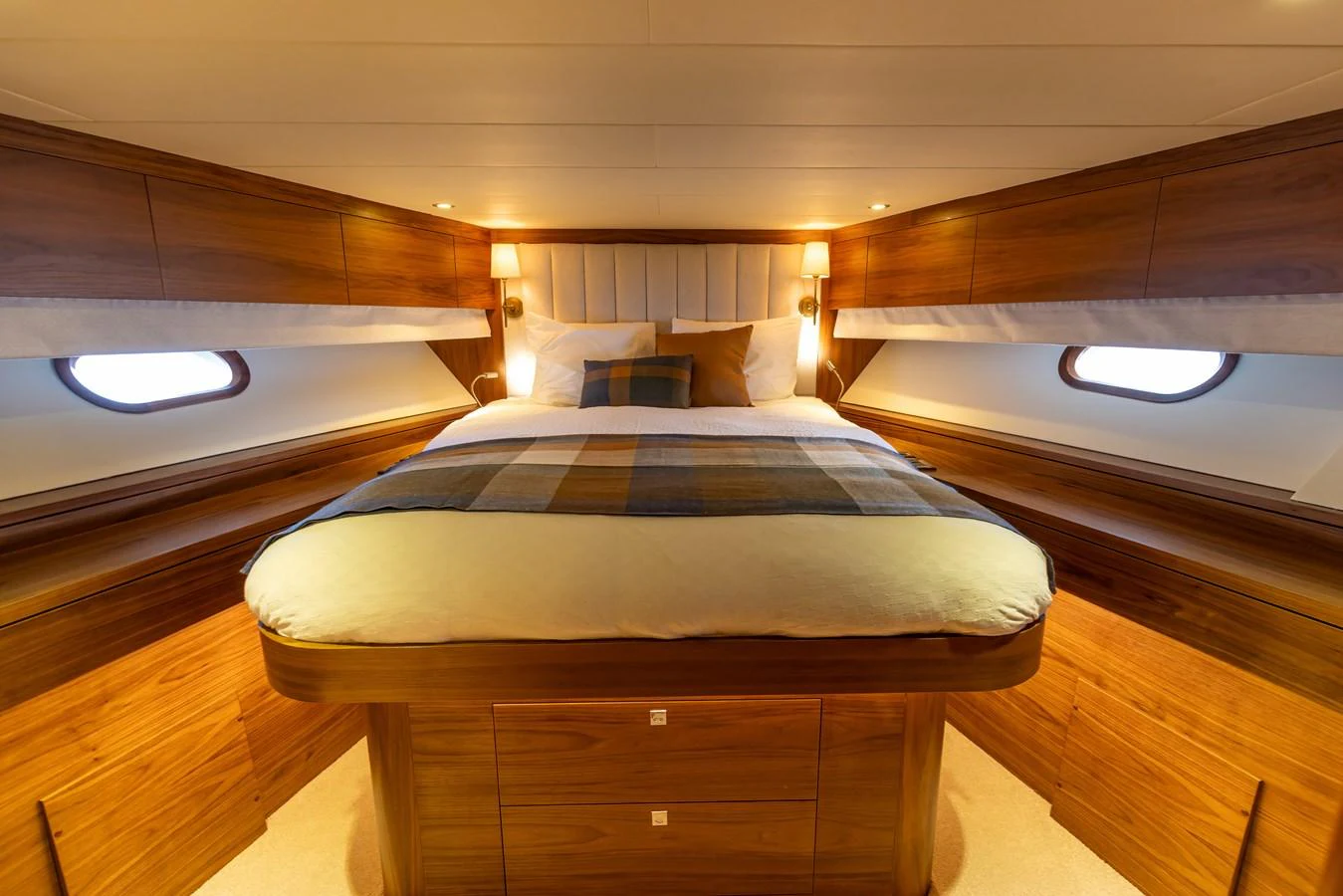 The stateroom features a cozy bed with warm wooden accents and ambient lighting. aboard DUTCHESS Yacht for Sale