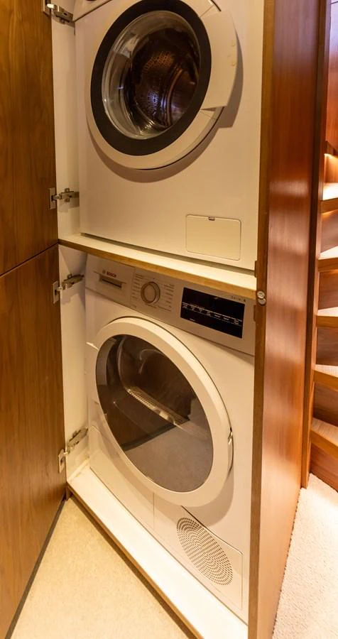 The yacht features a convenient laundry area with a stacked washer and dryer. aboard DUTCHESS Yacht for Sale
