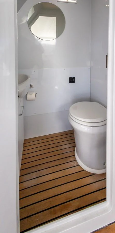 The yacht's head features a modern toilet and a round mirror above the sink. aboard DUTCHESS Yacht for Sale