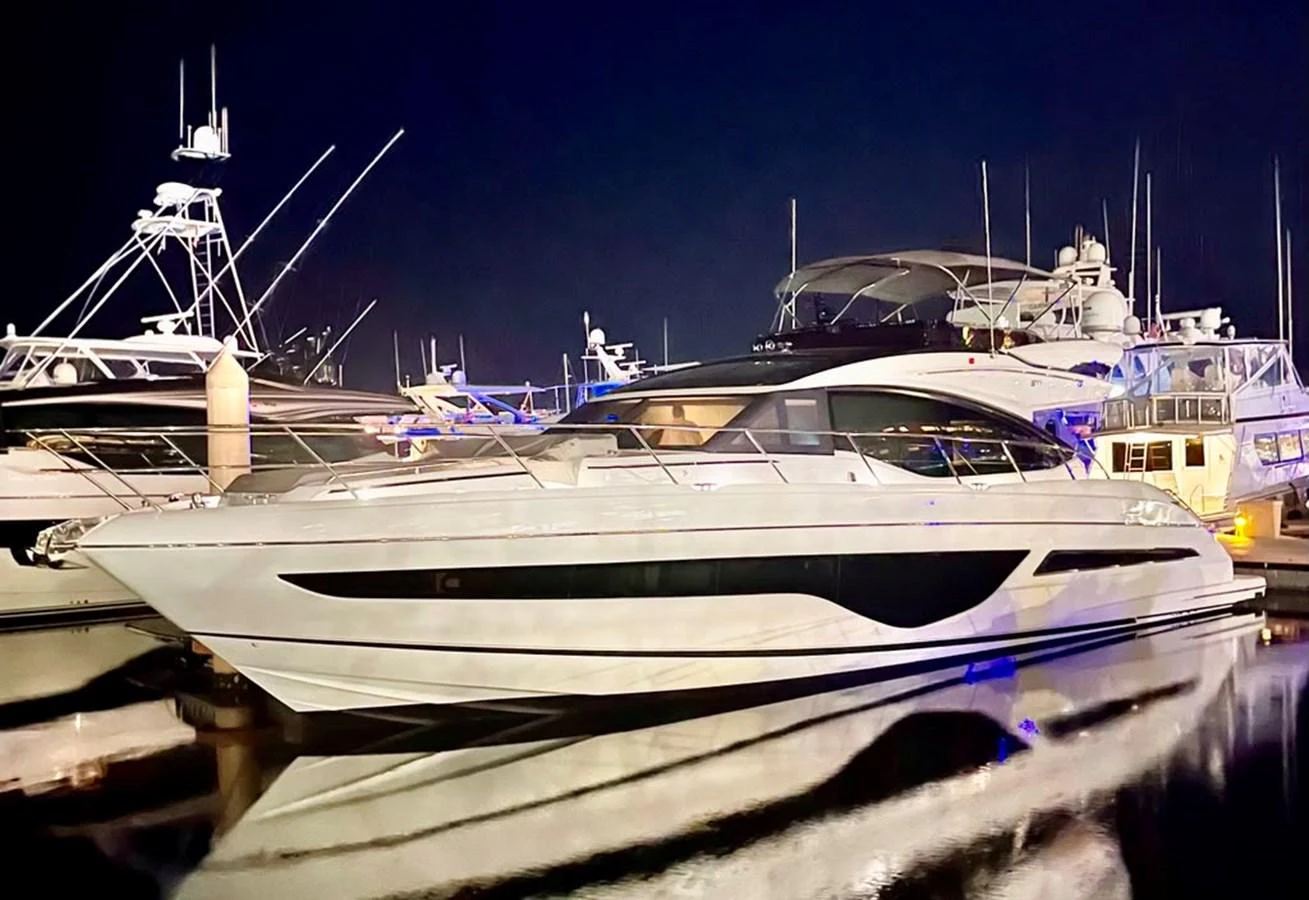 A sleek and modern yacht is docked at a marina, illuminated beautifully against the night sky. aboard WILE E COYOTE Yacht for Sale