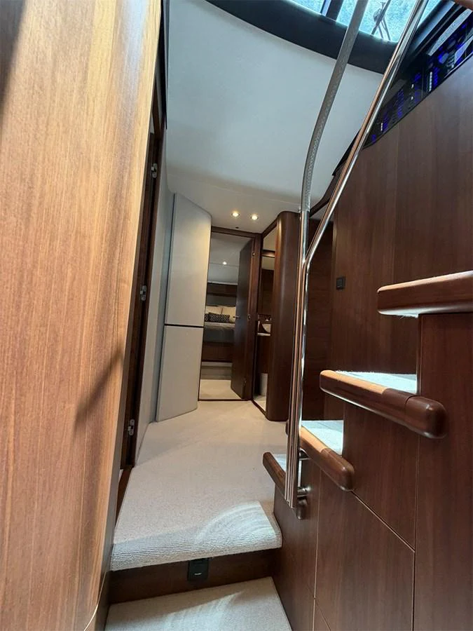 A warm and inviting interior staircase with wooden finishes leads to the lower deck. aboard WILE E COYOTE Yacht for Sale
