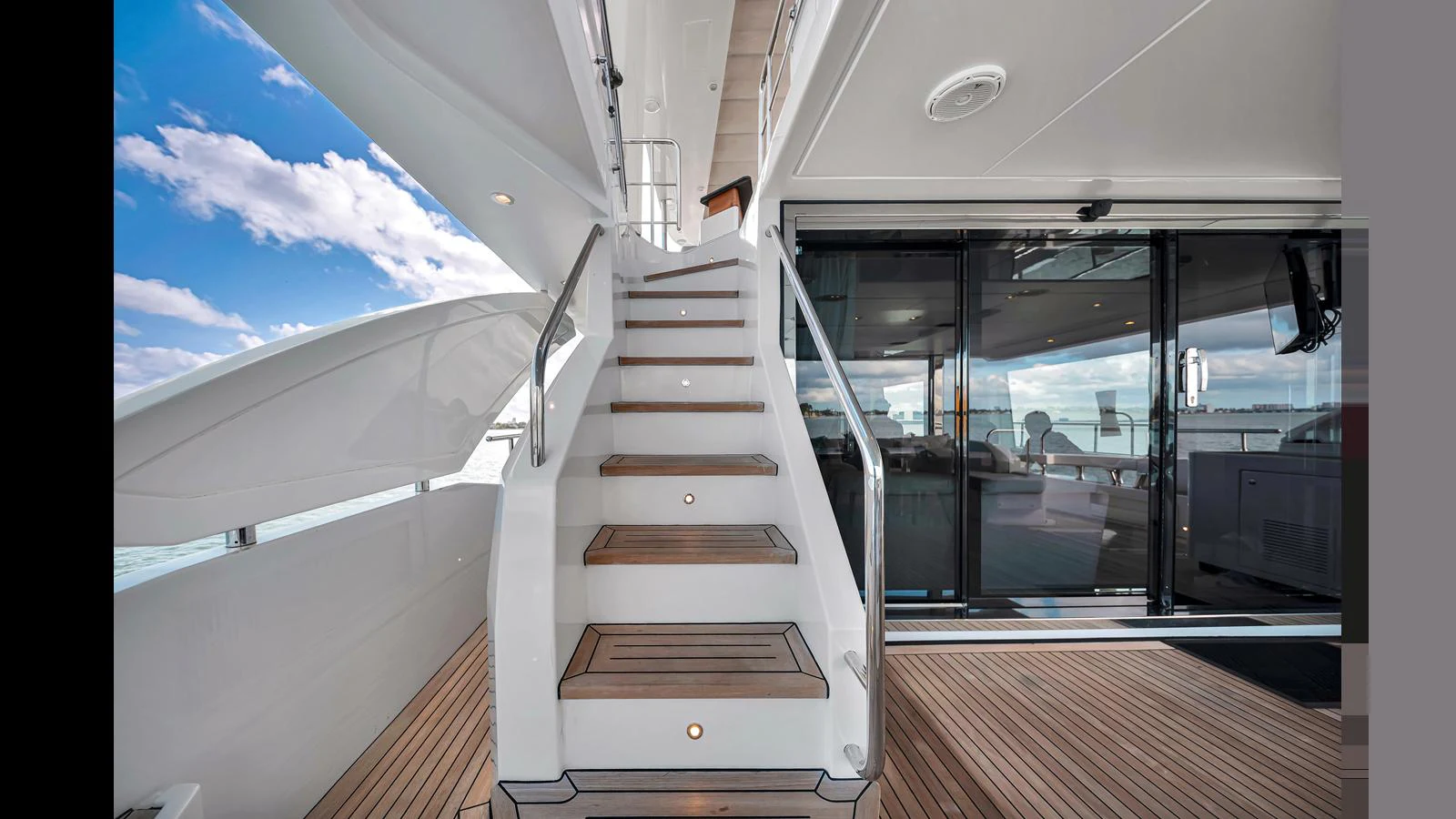 The aft deck features a sleek staircase leading to the upper levels, with a view of the sea and sky. aboard CLOUD 9 Yacht for Sale