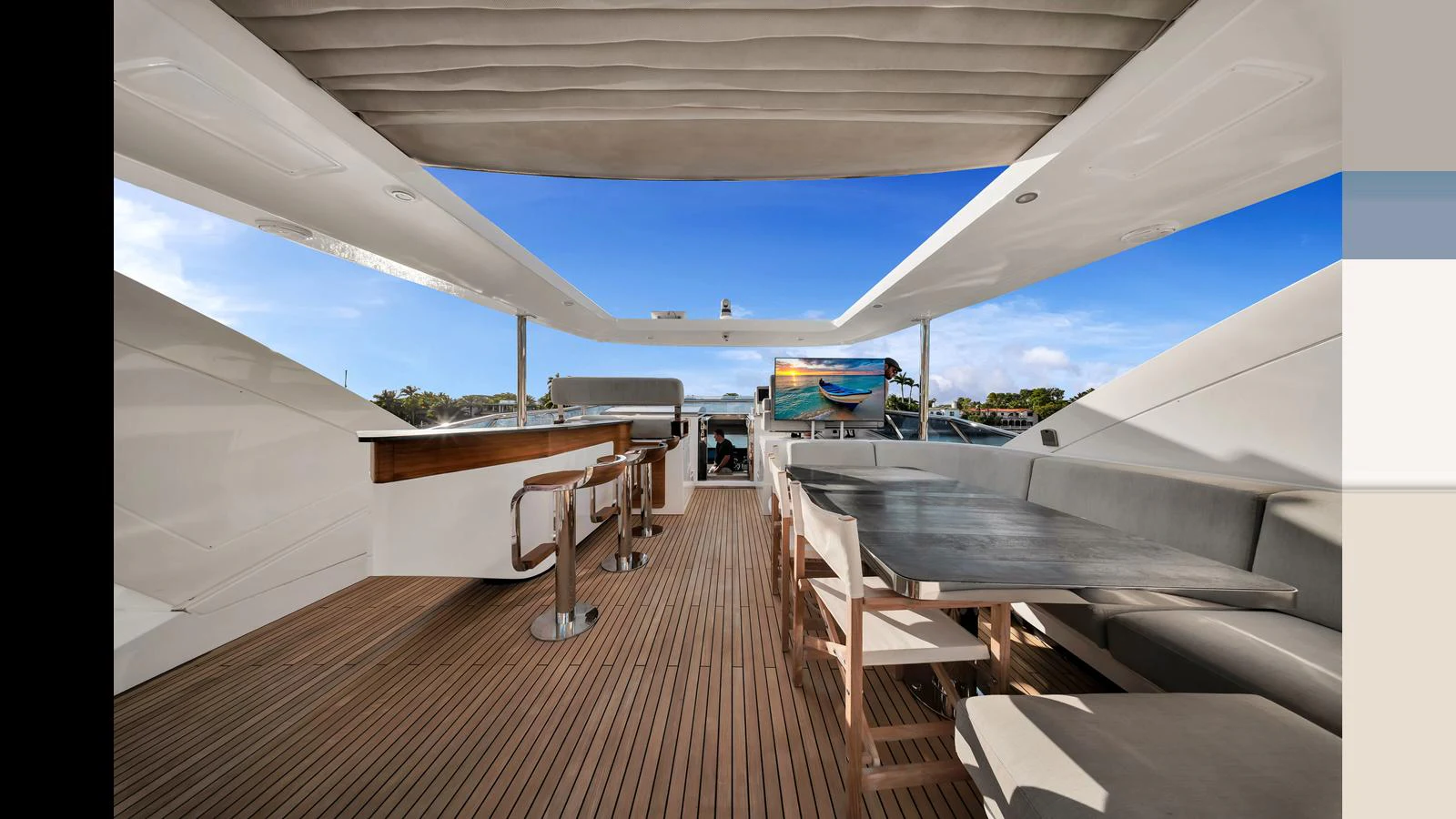 The flybridge offers a spacious seating area with a table and bar stools, perfect for outdoor relaxation and dining. aboard CLOUD 9 Yacht for Sale