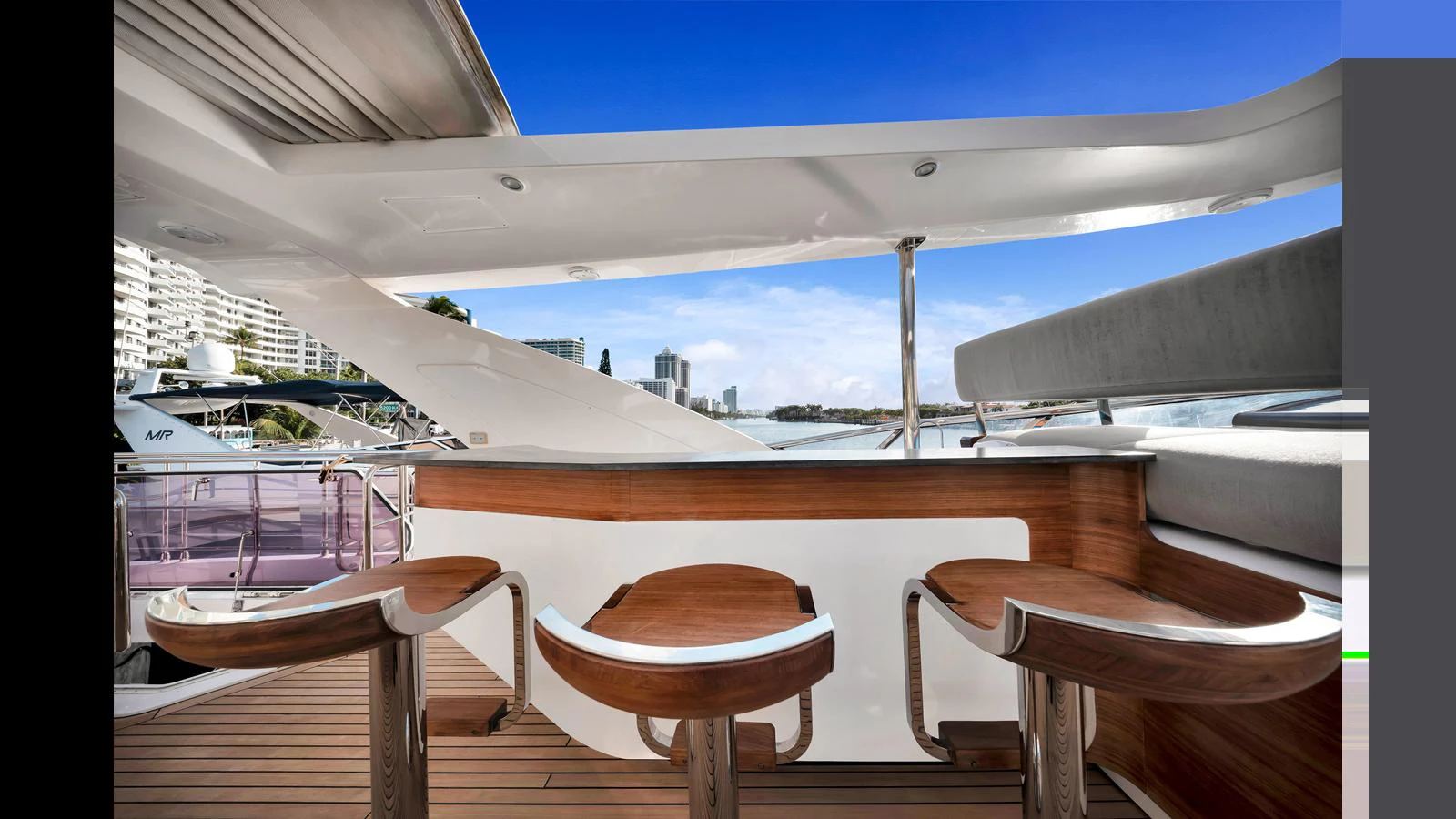 The yacht features a stylish outdoor bar area with modern stools and a beautiful view. aboard CLOUD 9 Yacht for Sale